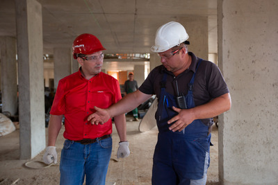 Zwei Männer mit Bauhelmen diskutieren auf einer Baustelle.